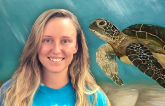 Artist Ashley Boggs in front of her Turtle Cove art